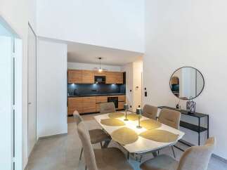 Discover modern living in this open-concept space, featuring a sleek, contemporary kitchen with warm wood cabinetry and dark countertops.
