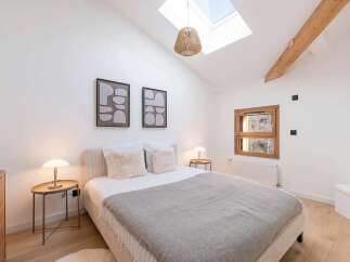 Experience serene comfort in this charming bedroom, featuring a cozy bed adorned with plush pillows and a soft grey blanket.