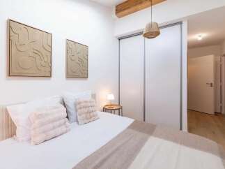 This modern bedroom features a comfortable bed adorned with plush pink throw pillows and crisp white linens.