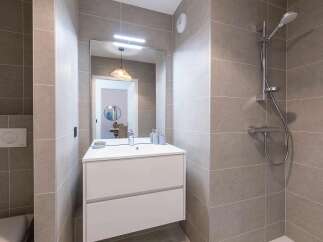 This modern bathroom features a sleek white vanity with ample storage, complemented by a large mirror with integrated lighting.