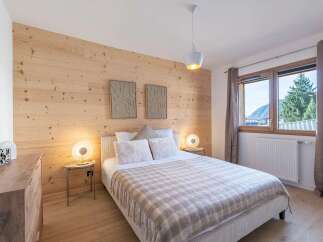 Experience cozy mountain living in this charming bedroom featuring a warm, wood-paneled accent wall that creates a rustic yet modern ambiance.