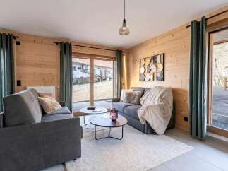 Experience modern living in this beautifully appointed living room, featuring a cozy grey sofa adorned with a plush cream throw and accent pillows.