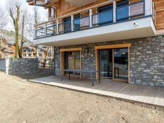 Experience modern living in this stunning property featuring a stone-clad lower level with expansive glass doors opening onto a wooden deck.