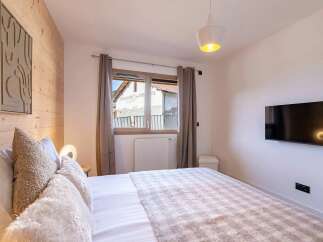 Experience ultimate comfort in this beautifully appointed bedroom, featuring a plush bed adorned with soft, textured pillows and a cozy throw blanket.