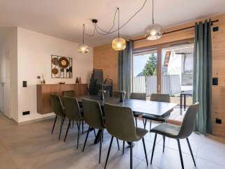 This spacious dining room features a large, modern table surrounded by comfortable, upholstered chairs, perfect for family gatherings.