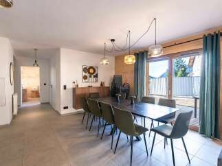 This spacious dining area features a large, dark wood table surrounded by plush, olive-green chairs, perfect for family gatherings.