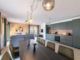 Experience modern living in this open-plan apartment, featuring a sleek, dark green kitchen with integrated appliances and a spacious dining area.