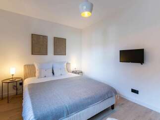 Experience modern comfort in this beautifully appointed bedroom, featuring a plush bed with crisp white linens and a cozy grey throw.