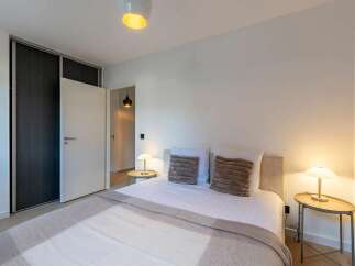 This modern bedroom features a comfortable bed with plush pillows and a cozy throw blanket, perfect for relaxation.