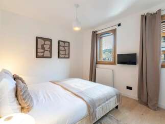Experience comfort and style in this inviting bedroom, featuring a plush bed adorned with soft pillows and a cozy throw blanket.