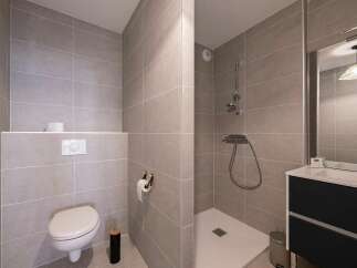 This modern bathroom features a sleek design with large grey tiles covering the walls and floor.