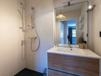 This modern bathroom features a sleek shower area with a chrome showerhead and a tiled wall.
