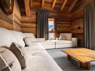 Experience rustic luxury in this mountain chalet living room, featuring warm wood paneling and exposed beams.