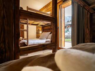 Experience cozy mountain living in this charming wooden cabin featuring a rustic bunk bed setup.
