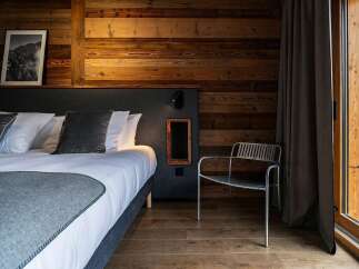 Experience rustic luxury in this charming bedroom, featuring a comfortable bed adorned with plush pillows and a cozy grey throw.