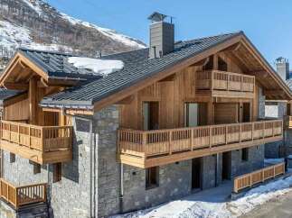 Experience luxury mountain living in this stunning chalet, featuring a modern stone and wood facade.