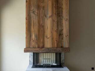 Experience rustic elegance with this stunning fireplace, featuring a dramatic wooden facade and a stone base.