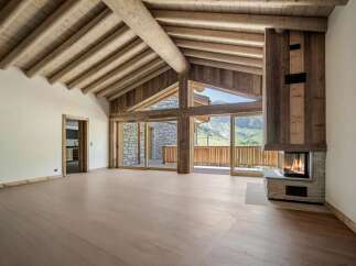 Experience the ultimate mountain retreat in this stunning chalet-style living room, featuring a grand vaulted ceiling with exposed wooden beams and a cozy stone fireplace.