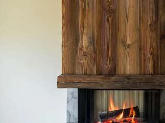 Experience the warmth and ambiance of a crackling fire in this stunning fireplace, featuring a rustic wooden facade and a modern stone base.