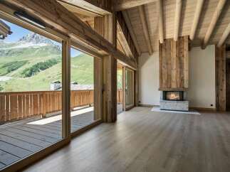 Experience luxurious mountain living in this stunning chalet featuring a grand fireplace and expansive wooden beams.