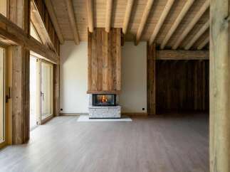 Experience rustic elegance in this spacious living area, featuring a stunning stone fireplace with a warm, crackling fire.