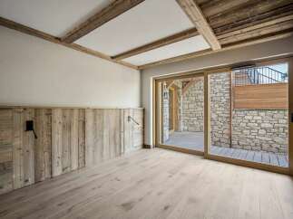 Experience rustic charm in this beautifully designed room, featuring exposed wooden beams on the ceiling and a unique wood-paneled accent wall.