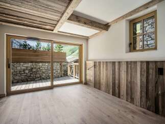 Experience rustic charm and modern comfort in this beautifully designed room, featuring a stunning wooden-beamed ceiling and a sliding glass door that opens to a scenic mountain view.