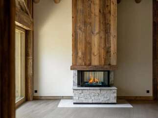 Experience rustic charm and modern comfort in this stunning living space, featuring a magnificent floor-to-ceiling wood-paneled fireplace as the focal point.