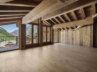 Experience luxurious mountain living in this stunning chalet-style interior, featuring exposed wooden beams and a vaulted ceiling that exude rustic charm.