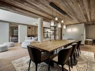 Experience luxurious mountain living in this stunning dining area, featuring a grand wooden table perfect for gatherings and illuminated by elegant pendant lights.