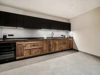 Experience modern living in this stunning kitchen featuring sleek black upper cabinets contrasted with rustic wooden lower cabinets.