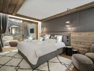Experience ultimate comfort in this luxurious bedroom, featuring a plush king-size bed adorned with soft white linens and a cozy faux fur throw.