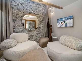 Experience modern mountain living in this stylish living area, featuring a unique stone accent wall and plush, contemporary seating.