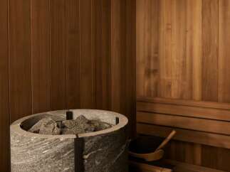 Experience ultimate relaxation in this luxurious sauna, featuring a modern stone heater filled with natural rocks.