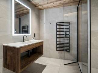 Experience modern luxury in this stunning bathroom, featuring a sleek floating vanity with a natural wood finish and a spacious countertop.