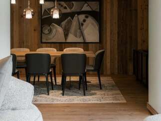 Experience rustic elegance in this dining area, featuring warm wood-paneled walls and a striking abstract artwork.