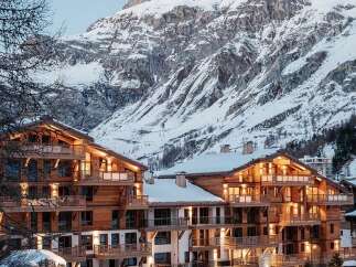 Experience luxury mountain living in this stunning alpine property, featuring a modern wooden facade and multiple balconies offering breathtaking views of the snow-capped peaks.