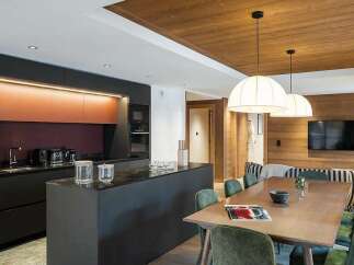 Experience modern luxury in this stunning open-concept living space, featuring a sleek, dark-toned kitchen with integrated appliances and a striking copper backsplash.