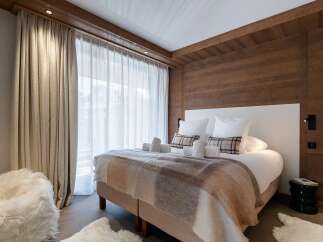 Experience ultimate comfort in this luxurious bedroom, featuring a plush bed adorned with soft linens and a cozy plaid throw.