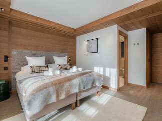 Experience ultimate comfort in this beautifully appointed bedroom, featuring a plush king-sized bed adorned with crisp white linens and accent pillows.