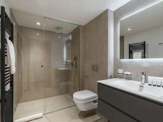 This modern bathroom features a spacious walk-in shower with glass enclosure, a wall-mounted toilet, and a sleek vanity with a large illuminated mirror.