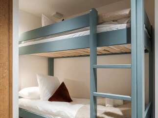 Discover cozy sleeping arrangements with this charming blue bunk bed, perfect for maximizing space in a bedroom.