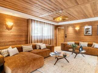 Experience luxurious mountain living in this stunning chalet-style living room, featuring warm wood paneling throughout and a cozy, inviting atmosphere.