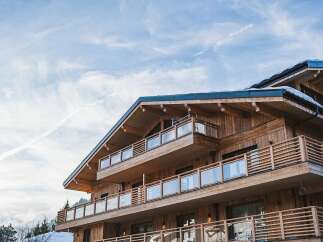 Experience luxury mountain living in this stunning wooden chalet, featuring multiple levels of spacious balconies with modern glass railings.