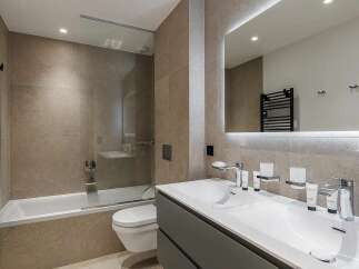 Experience modern luxury in this impeccably designed bathroom, featuring a sleek bathtub with a glass enclosure and a stylish dual vanity.
