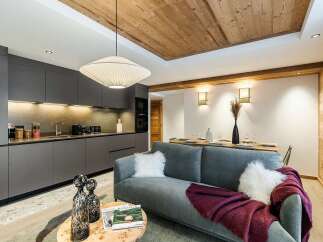 Experience modern alpine living in this beautifully designed open-concept space, featuring a sleek grey kitchen with integrated appliances and ample storage.