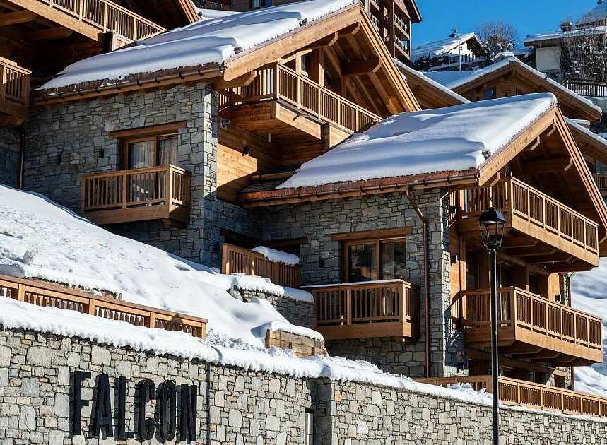 Experience luxury mountain living in this stunning chalet, featuring a stone facade and warm wooden accents.