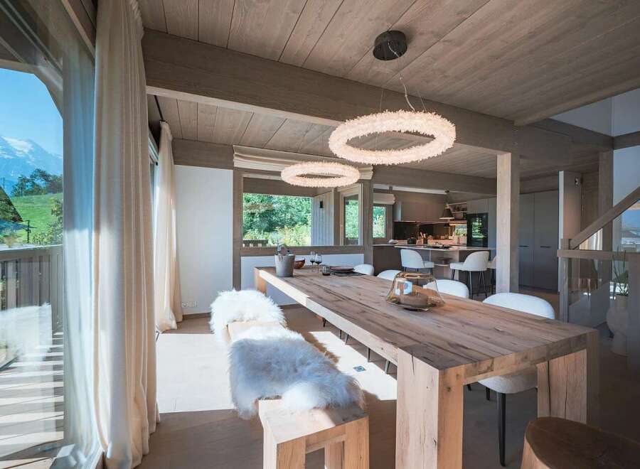 Experience luxurious mountain living in this stunning dining area, featuring a rustic wooden table and plush seating, perfect for intimate gatherings.