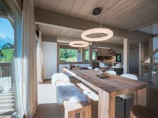 Experience luxurious mountain living in this stunning dining area, featuring a rustic wooden table and plush seating, perfect for intimate gatherings.