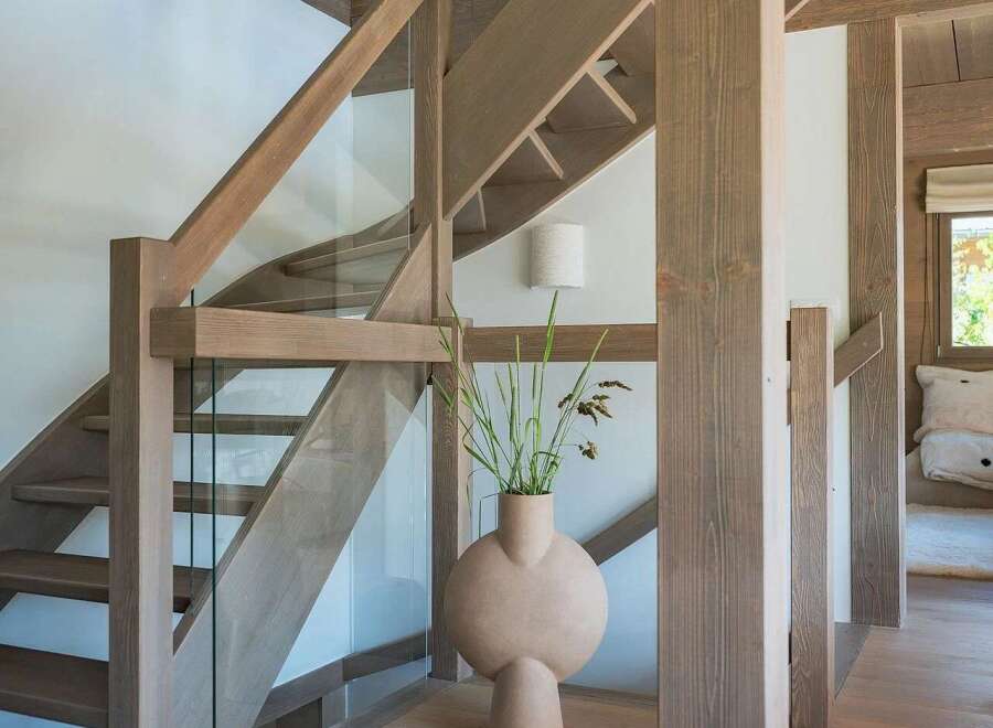 Experience modern living with this stunning staircase featuring natural wood beams and sleek glass railings.